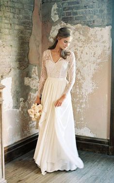 a woman in a wedding dress standing next to a wall with peeling paint on it