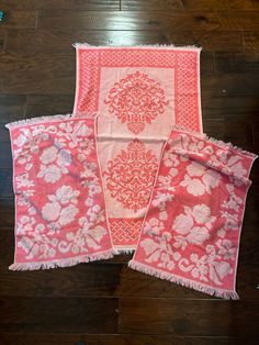 three pieces of pink and white fabric with flowers on them sitting on a wooden floor