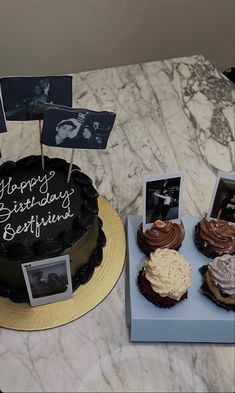 a table topped with cakes and cupcakes covered in frosting next to photos