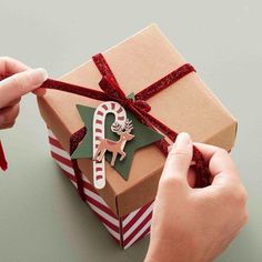 someone wrapping up a christmas present with a ribbon and ornament on the top