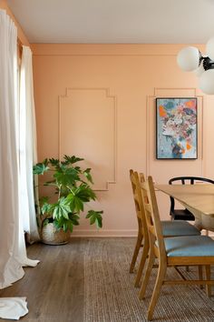 a dining room with pink walls and wood flooring is seen in this image, there are several chairs around the table