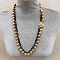 I love the elegant look of these vintage 1960 glass and metal bead necklaces. This one is a two strand necklace of 7mm faceted black glass beads mixed with 10mm brushed goldtone ball beads. The necklace measures 26 inches long. There is a lovely flower atop a box clasp and the piece is not signed by the maker. It is in excellent, near mint condition. How pretty this would look with a simple black dress or tunic top. This will arrive in a lovely gift box for easy gift giving or safe storage. If y Gold Beaded Necklaces With Black Beads For Evening, Gold Beaded Necklace With Black Beads For Evening, Gold Beads Jewelry For Evening, Elegant Double Strand Gold Beads, Gold Necklaces With Round Beads For Evening, Elegant Gold Beads With Black Details, Evening Beaded Necklaces With Polished Round Beads, Polished Beads Necklace For Evening, Evening Necklace With Polished Beads