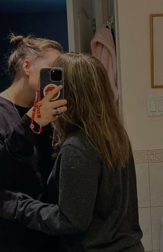 a woman taking a selfie with her cell phone in front of a bathroom mirror