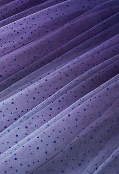 closeup of purple fabric with blue polka dots on the top and bottom, as seen from above