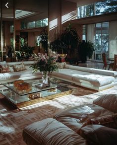 a living room filled with lots of white furniture and large mirrors above the couches