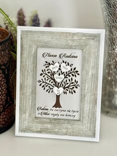 a wooden frame with a family tree and two hearts on it, sitting next to a potted plant