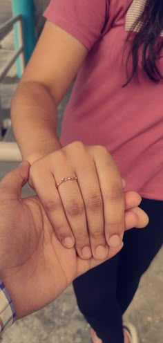 a person holding the hand of another person with a ring on their finger in front of them