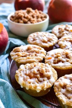 there are some muffins on a plate with apples in the background