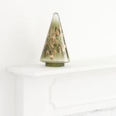 a green vase sitting on top of a white mantle