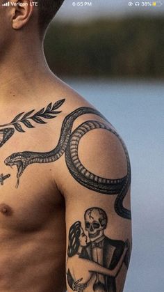 a man with a snake tattoo on his arm and shoulder is looking at the camera