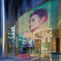 an advertisement on the side of a building with a woman's face reflected in it