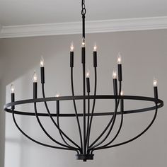 a black chandelier with candles hanging from it's centerpiece in a room