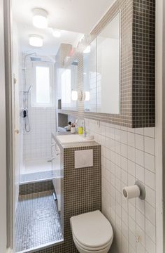 a white toilet sitting under a bathroom mirror next to a sink and bathtub in a bathroom