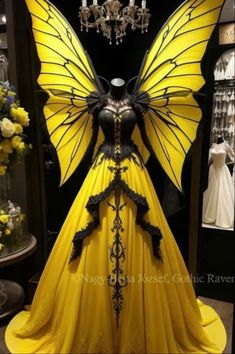 a yellow and black butterfly costume on display in front of a chandelier filled with flowers