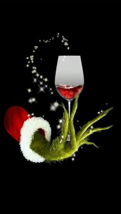 the grin's hand is holding a wine glass with red liquid in it, while wearing a santa hat