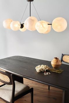 a dining room table that has some lights hanging from it