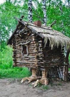 an old log cabin in the woods is made out of branches and logs, with grass on top