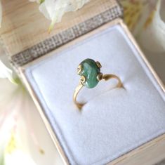 Dark green and gold create an emerald ring that sings with elegance and stands for bravery. The adjustable ring easily fits various ring sizes. The 14k gold filled metal setting creates a long-lasting and hypoallergenic ring. Each handmade pair uses a three step adhering process to guarantee durability and quality, Hypoallergenic material guarantees no reaction when you wear them. As no raw stone is the same, each emerald ring has a slightly different shape and size guaranteeing uniqueness and i Gold Crystal Promise Ring For May Birthstone, Adjustable Elegant Jade Rings, Adjustable Open Emerald Ring For Promise, Adjustable Emerald Promise Ring, Adjustable Open Emerald Ring For Wedding, Elegant Gold Jade Ring, Adjustable Oval Emerald Rings, Adjustable 14k Gold Emerald Ring, Green Crystal Open Ring In 14k Gold