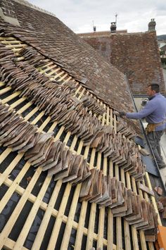 a man is working on the roof of a house with wood shingles and tile