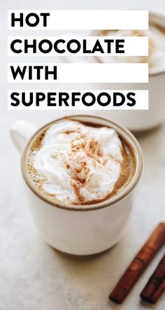 hot chocolate with superfoods in a white mug next to cinnamon sticks on a table