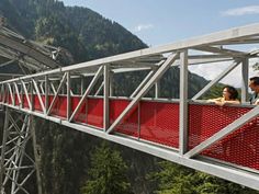 two people are standing on a red bridge