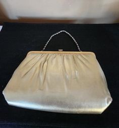 Mardane, a U.S.A. producer of specialized handbags utilized many Adair French designs. This one is a soft, pliable gold leather with cross-hatch gold finish frame. Snap finger closure.  Lined in pale gold satin with small change purse on elastic cord within. Lightweight chain handle. Small cologne stain inside but very clean. No tears or mars. Also has two moon attachments on frame called handkerchief hooks. Lovely dressy look for evening. Chain fits inside to convert to clutch. Rare Mardane des Classic Gold Shoulder Bag, Classic Gold Bags With Gold-tone Hardware, Vintage Gold Shoulder Bag For Party, Classic Gold Shoulder Bag For Evening, Classic Party Clutch With Gold-tone Hardware, Elegant Rectangular Bag With Gold Clasp, Elegant Rectangular Bags With Gold Clasp, Classic Formal Bag With Gold Clasp, Classic Formal Bags With Gold Clasp