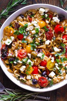 a white bowl filled with pasta salad on top of a wooden table