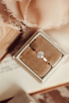 an engagement ring sitting on top of a book next to a piece of paper and lace