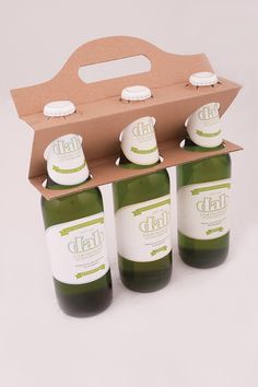 six bottles of green liquid in a cardboard box with the lid open and labels on them