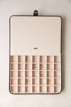 an open case with several pairs of rings in it on a white wall next to a pair of glasses