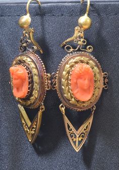 "Holding you spellbound, this captivating Victorian coral cameo pin and earring set are exceptional. The set dates from the late 1880's. It is set in 14k yellow gold. The elaborately detailed raised carving of a Victorian young lady is a masterful work of art. The gold frame is intricate and extravagant filled with braided gold and artistic open work. The pin can easily be converted in to a pendant. The pin measures 2 ¾\" long and 2\" wide. The matching earrings are equally dramatic and stunning Victorian Oval Pierced Earrings, Antique Evening Earrings For Pierced Ears, Antique Handmade Evening Earrings, Antique Wedding Cabochon Earrings, Antique Handmade Earrings For Evening, Vintage Cameo Drop Earrings, Antique Yellow Gold Cabochon Earrings, Oval Cabochon Earrings For Evening, Victorian Cameo Earrings For Gift