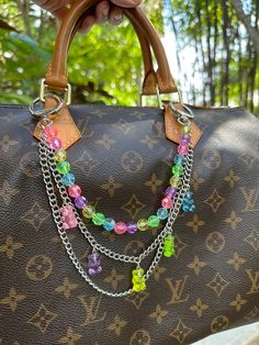 a hand holding a brown purse with multicolored beads and chains attached to it