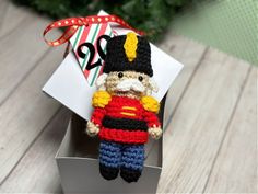 a crocheted nutcracker ornament in a box with a ribbon