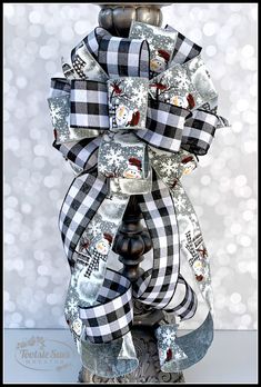 a close up of a christmas bow on a pole with snowflakes in the background