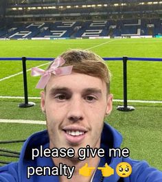 a man with a pink bow on his head is taking a selfie at a soccer field