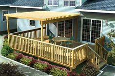 a wooden deck and table in front of a blue house