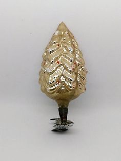 a gold christmas tree ornament sitting on top of a white table next to a black object