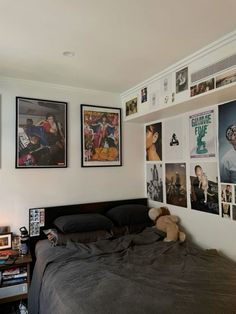 a bed sitting in a bedroom next to a wall with pictures on it and a teddy bear