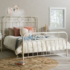 a white metal bed sitting on top of a wooden floor