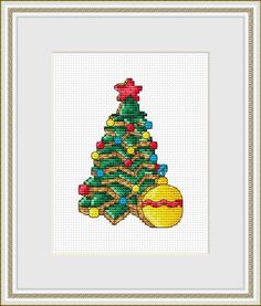 a cross stitch christmas tree with ornaments on it's base and a gold frame