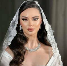 a woman wearing a bridal gown and veil with her hair pulled back in a half - up style