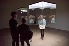 three people standing in front of mirrors with their hair flying through the air and looking at them