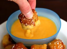 a person dipping some kind of food into a blue bowl with other foods in it