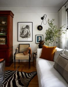 a living room with white couches and pictures on the wall above them, along with zebra rugs