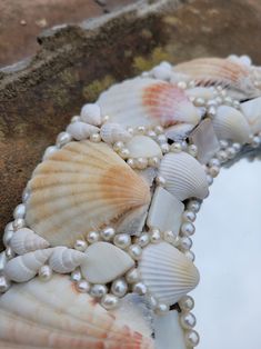 seashells and pearls are arranged on the edge of a stone wall in front of a mirror