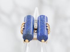 Indulge in luxury with this ring! The intricate cylindrical lapis stones paired with sparkling diamond accents creates a statement piece that exudes sophistication and exclusivity. Elevate any outfit with this elegant and timeless ring.Metal: 14K Yellow GoldGem: 2 LapisGem Measurements: 7.6 x 20.1 mm, Cylindrical Accents: 7 Diamonds totaling .10 Carats, VS in Clarity, H-I in ColorRing Size: 4.75Marks: "14K 585" Stamped on the inside band Luxury Formal Rings With Stones, Luxury Rings With Stones, Lapis Ring, Pocket Watch Chain, Watch Chain, Sparkle Diamonds, Pearl Pendant, Beaded Chain, Charm Earrings