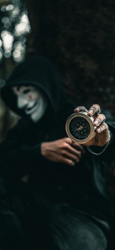 a person in a black hoodie holding a clock