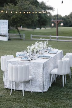 the table is set with white flowers and place settings