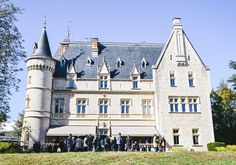 people are standing in front of a large castle like building with turrets and blue windows