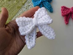 three crocheted bows are being held in the palm of someone's hand